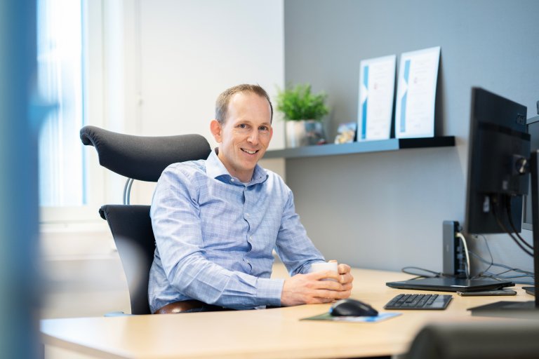 Jeroen Hoff som sitter foran en datamaskin med en kaffekopp i hånden